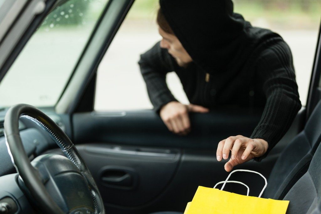 a car thief reaching into the car to steal a valuable item