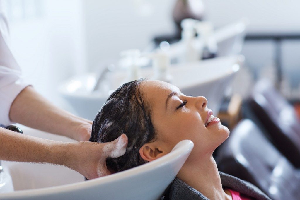 happy young woman with hairdresser washing head