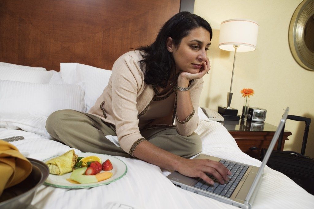 woman working and eating on the bed
