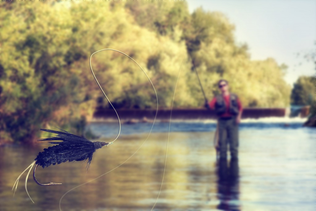 A person fly fishing in a river with a fly in the foreground