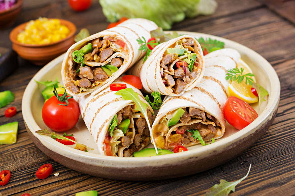 meat and vegetable wrap plated with fresh tomatoes