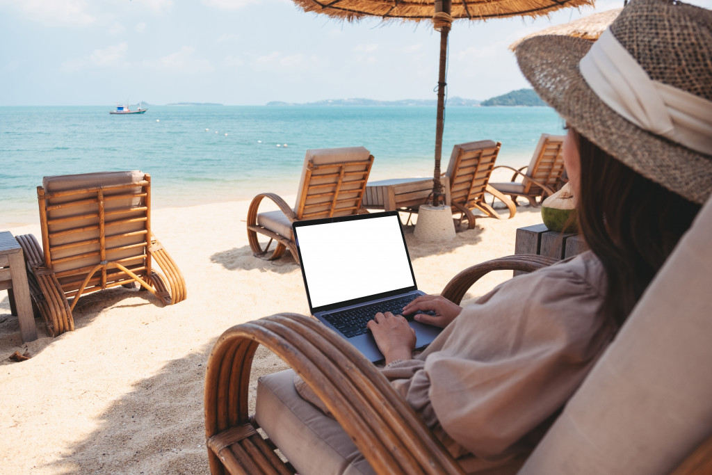 woman using her laptop while on the beach