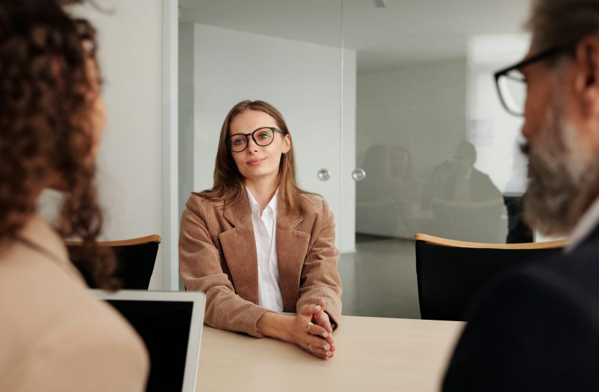 smiling woman with glasses facing a panel of interviewers during a job interview