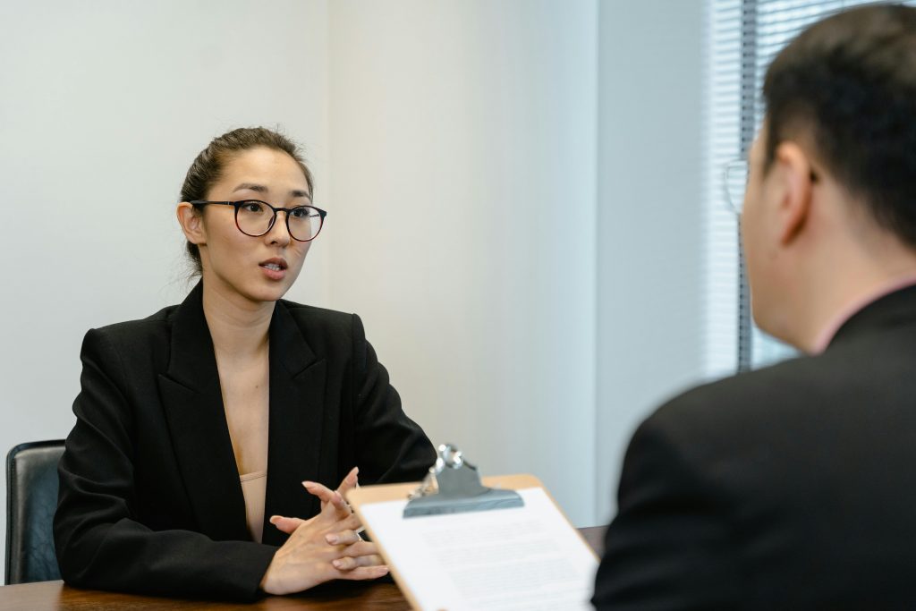 woman wearing glasses and business attire speaking during a job interview