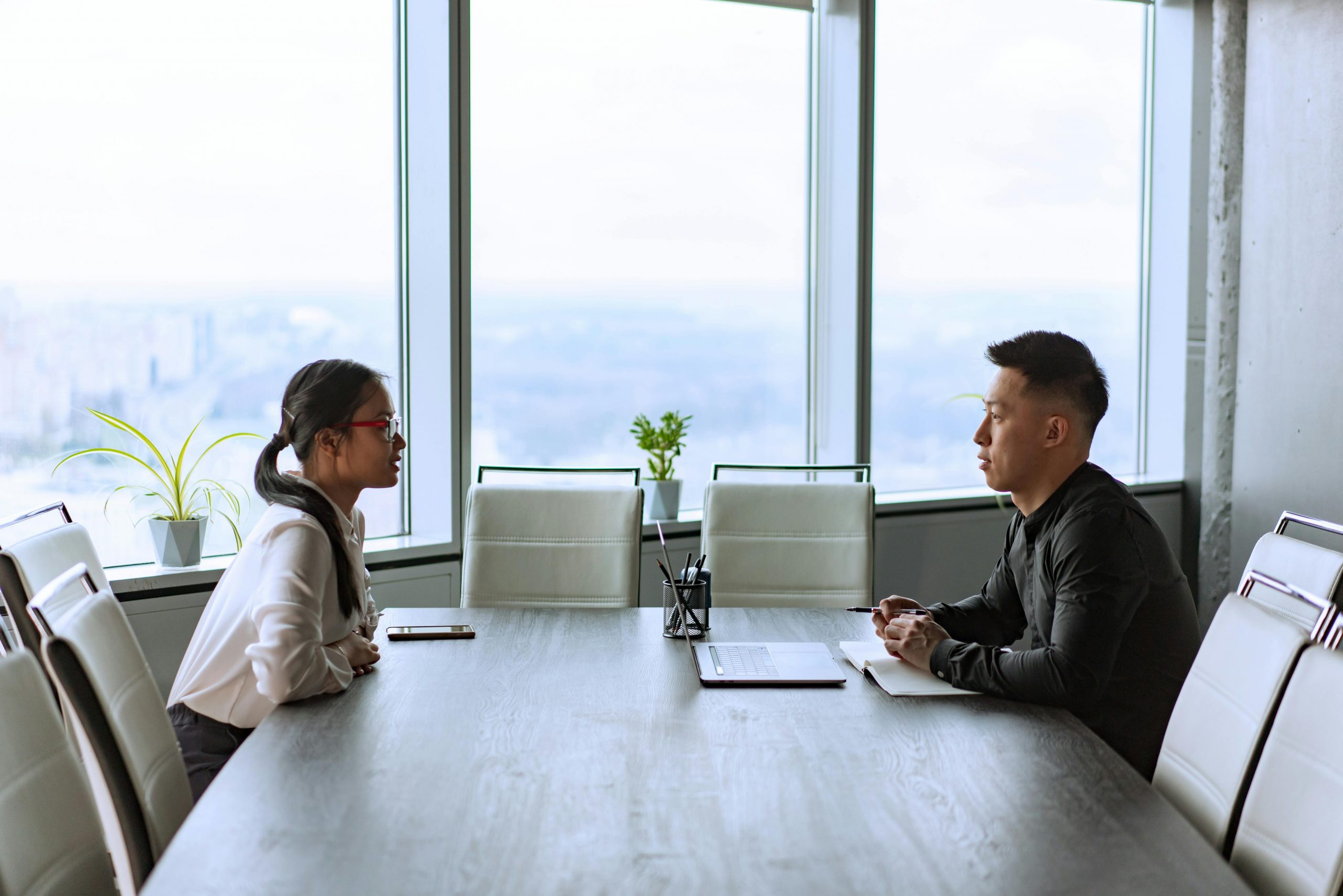 female interviewee and male interviewer seated at a long table by large windows